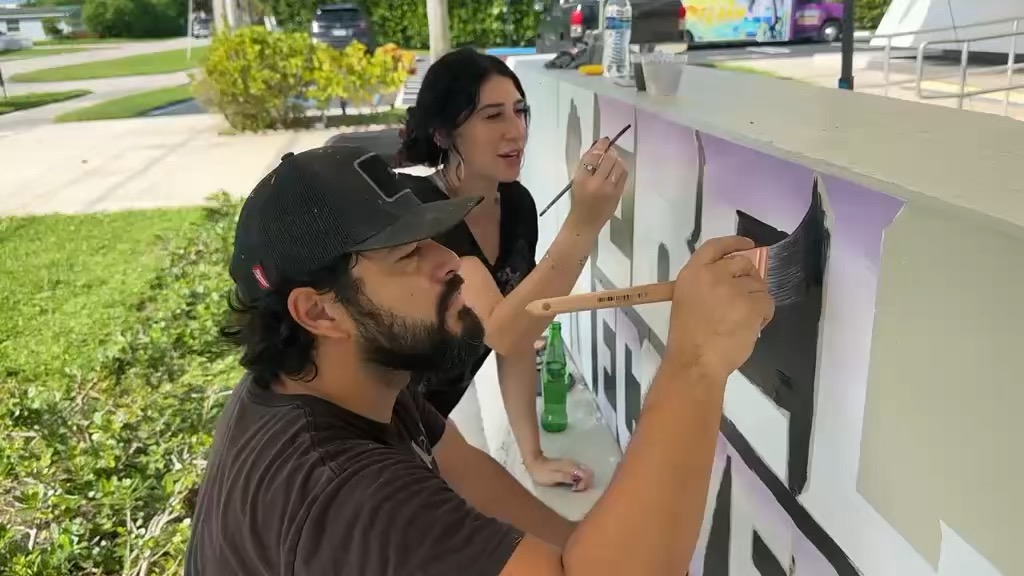 Volunteers painting the lettering on the sign