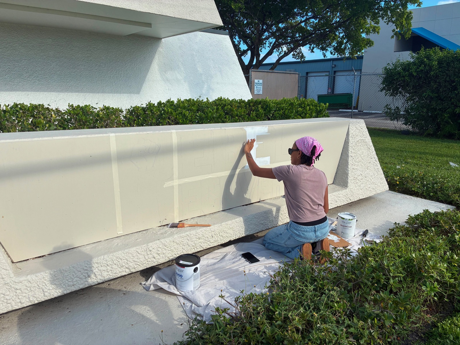A volunteer taping off the blank sign before painting
